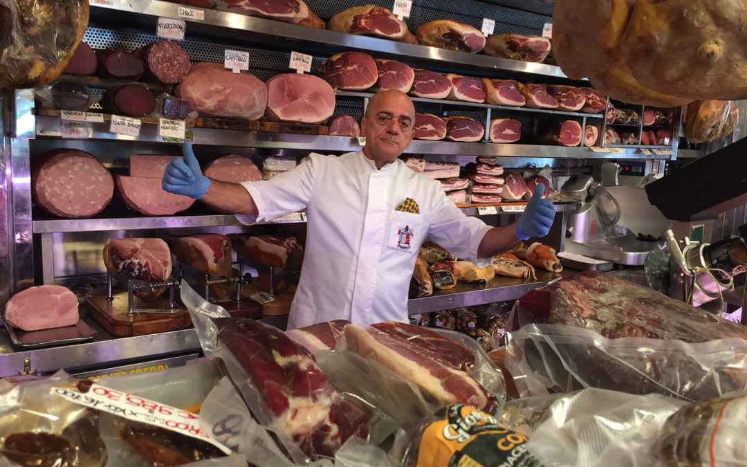 Butcher shop in Rome with gentleman behind the butcher counter that displays various meats in Rome